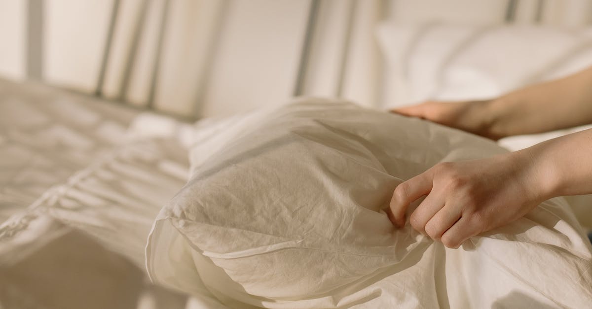 How to get clean bed linens at hotels? - Person Holding White Textile on Bed