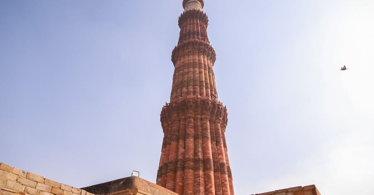 How to get from Delhi to Kathmandu overland? - From below of ancient ornamental brick tower of Qutb Minar against cloudless blue sky located in historic complex in Delhi