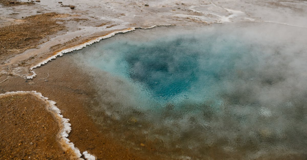 How to get from Iceland to Greenland? - High angle picturesque scenery of hot geyser with crystal clear blue water on sandy terrain