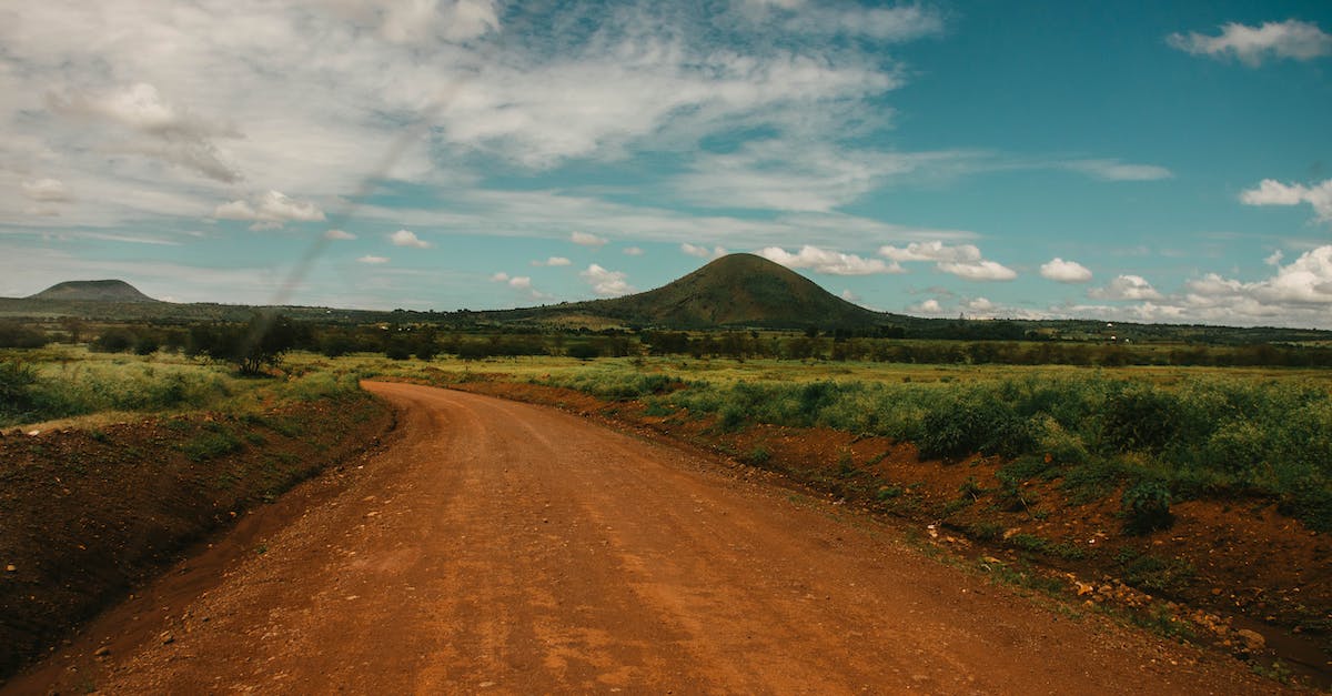 How to get into and travel across Tanzania - Photo of Dirt Road Across Hill Under Cloudy Sky