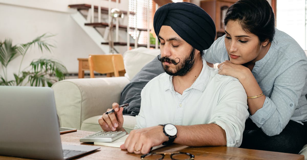 How to get live running status of an Indian train? [closed] - Focused Indian woman standing behind man in turban at table counting with calculator while writing notes in notepad