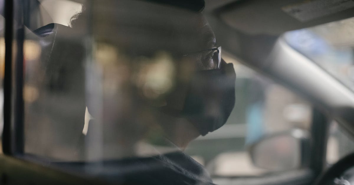 How to get safe through Mauritania - Through glass of crop concentrated ethnic man in eyeglasses sitting in car and wearing medical mask because of coronavirus pandemic