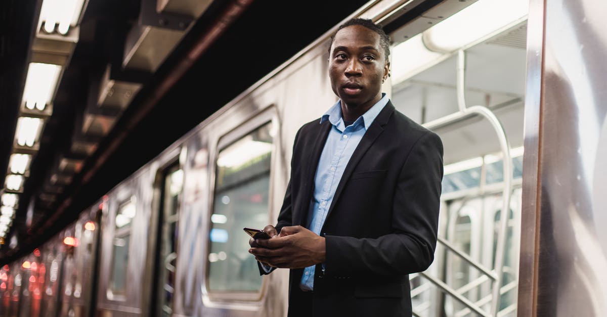 How to get to Vlkolínec by public transport? - Serious African American man in office wear with mobile phone in hands getting off underground train