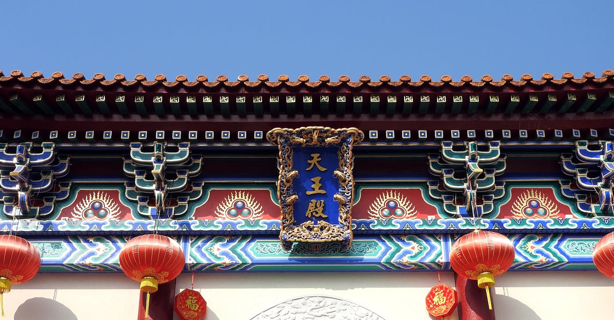 How to go from Vladivostok to Beijing by land? - From below of colorful Beijing Dongyue Temple located in Beijing in China decorated with red lanterns and ornaments with hieroglyphs and decorative elements in sunny day under blue cloudless sky