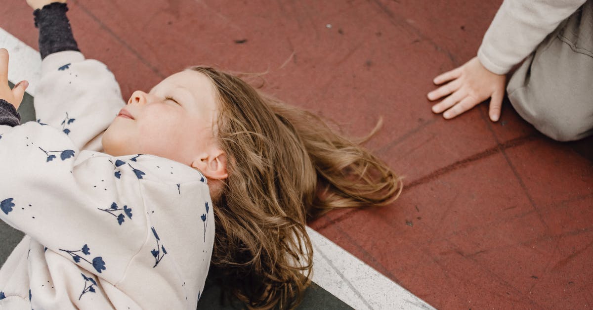 How to have fun in Bouillon, Belgium [closed] - Top view of playful little girl with closed eyes lying in colorful sports ground near unrecognizable kid while having fun together