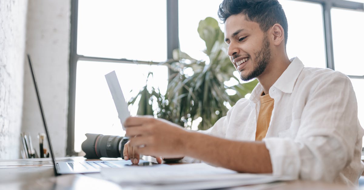 How to look for a photography "fixer" in Brazil? - Happy ethnic man looking at printed picture at desk