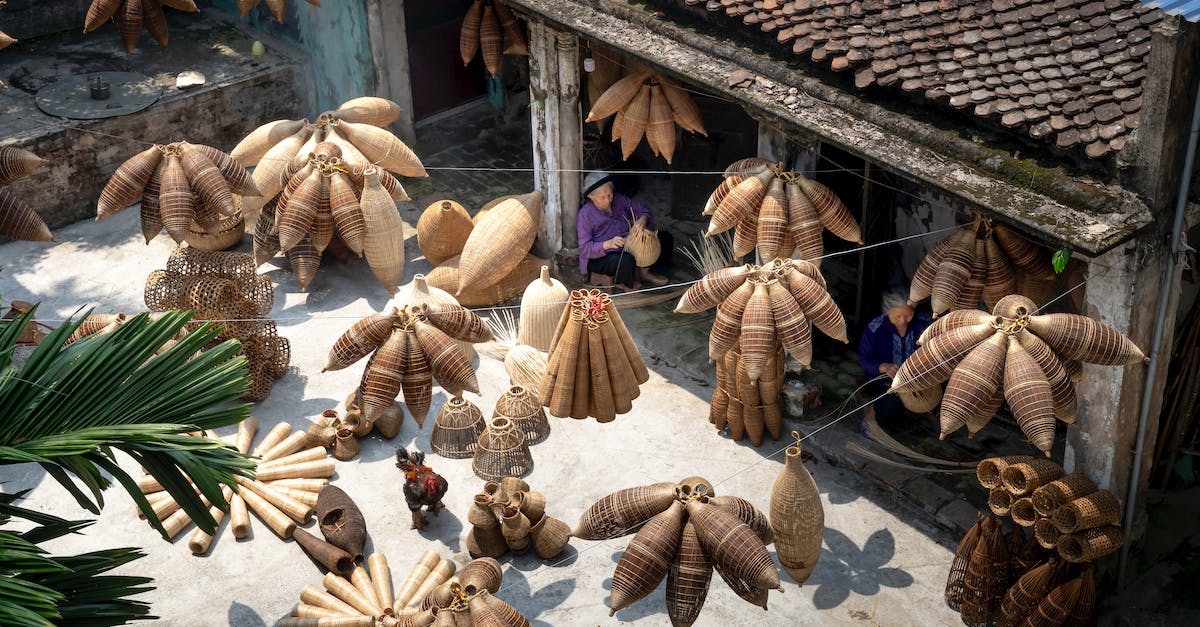 How to make ear plugs work in the tropics - From above of people sitting and making bamboo fish traps while working on local bazaar in Vietnam in daylight