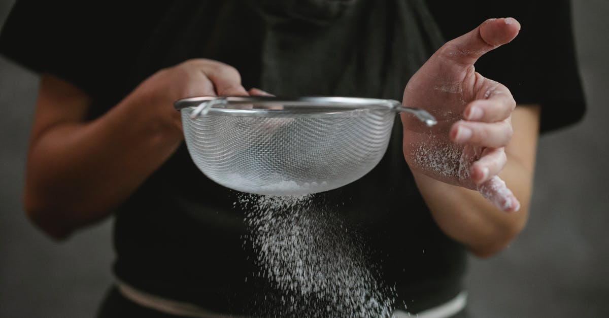 How to make ear plugs work in the tropics - Crop anonymous cook in apron sifting flour while preparing baking dish against gray background