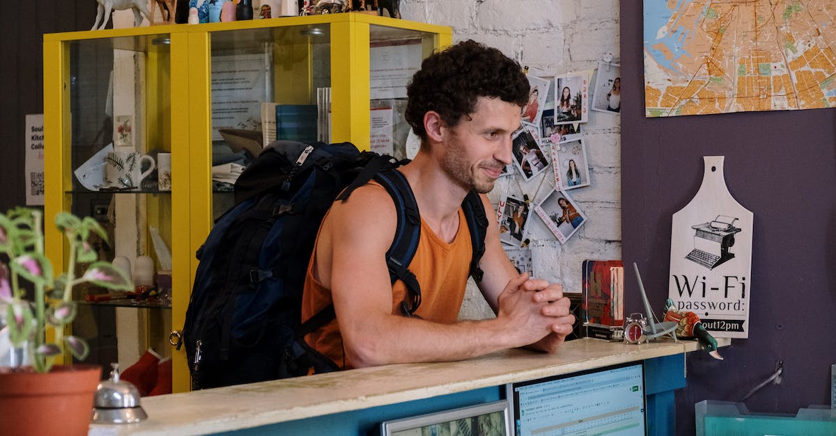 How to make the most of my first hostel stay - Man in Orange and Black Tank Top Sitting on Chair