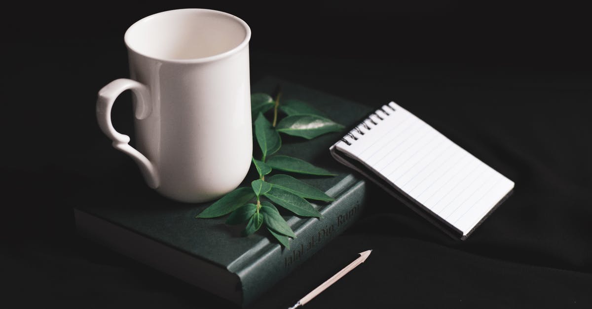 How to manage Hahn Air bookings? - From above composition of white cup placed on black leather diary near opened spiral notebook with blank sheets and pencil