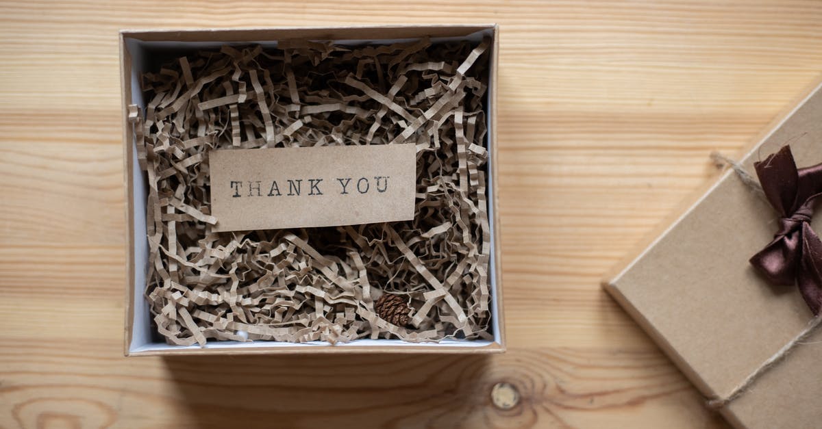 How to properly pack a box of pineapples? - Top view of opened carton present box with small postcard with Thank You inscription and paper stuffing on wooden table