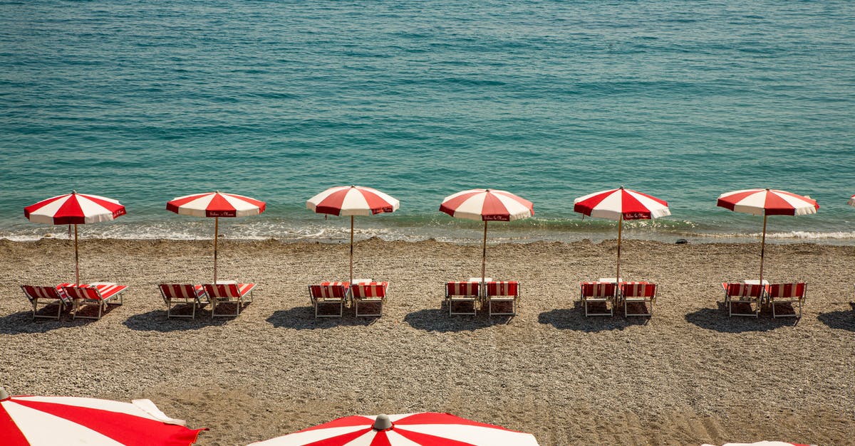 How to protect electronics on a beach holiday/vacation [closed] - Rows of red and white umbrellas on clean beach