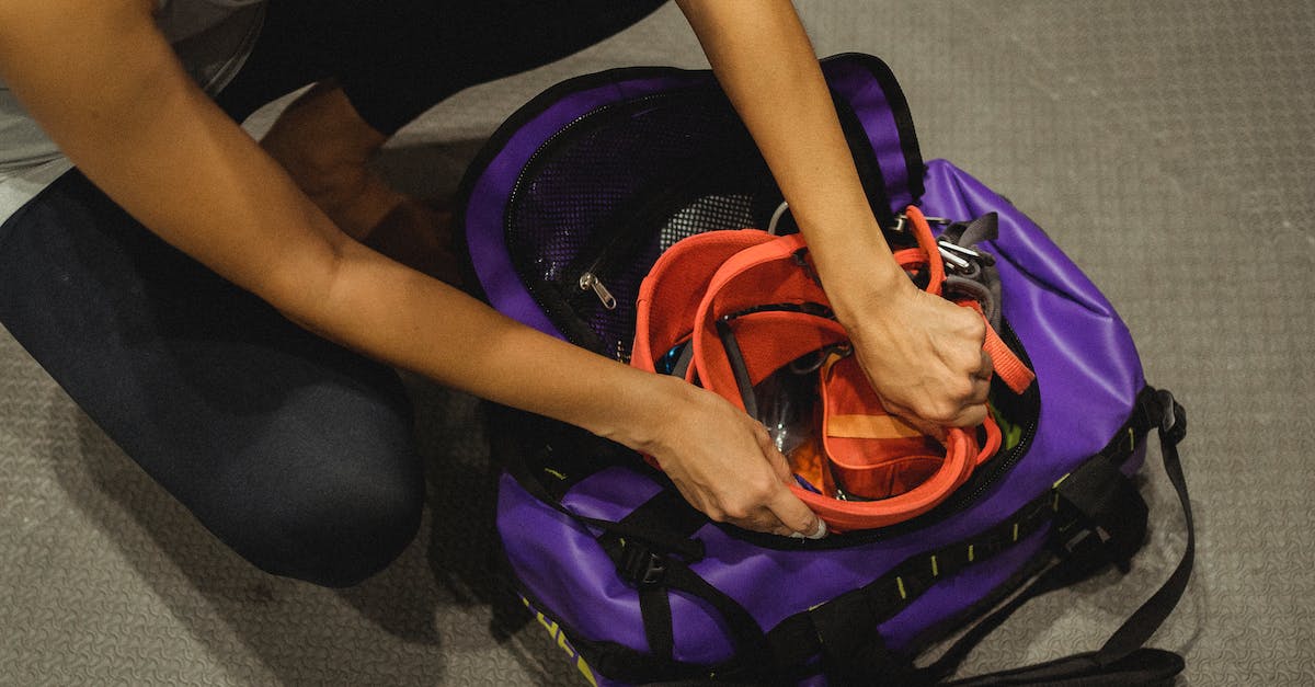 How to protect my gear during a monsoon? - From above of crop anonymous female athlete sitting on floor and packing safety belt in bag after training in contemporary gym