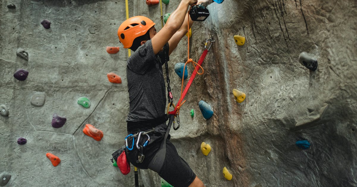 How to protect my gear during a monsoon? - Strong climber preparing climbing wall with screwdriver in gym