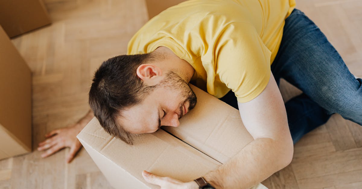 How to purchase United Airlines domestic tickets from South Africa? - High angle of fatigued male in casual wear sleeping on floor with cardboard box after packing belongings before moving out