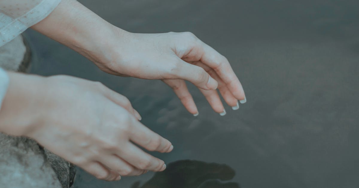 How to reach BSL airport from Freiburg by mid-morning? - Crop anonymous female in elegant clothes reaching hands to calm water in daytime