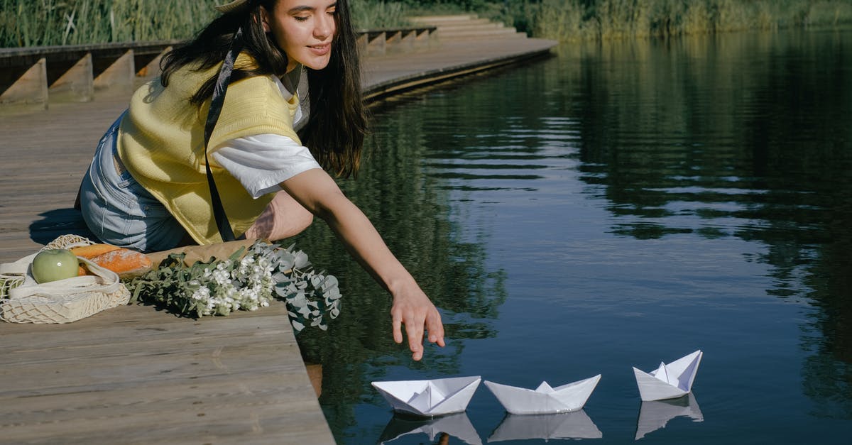 How to reach the clearest lake in the world? - Woman on Wooden Dock Reaching the Floating Paper Boats on Lake 