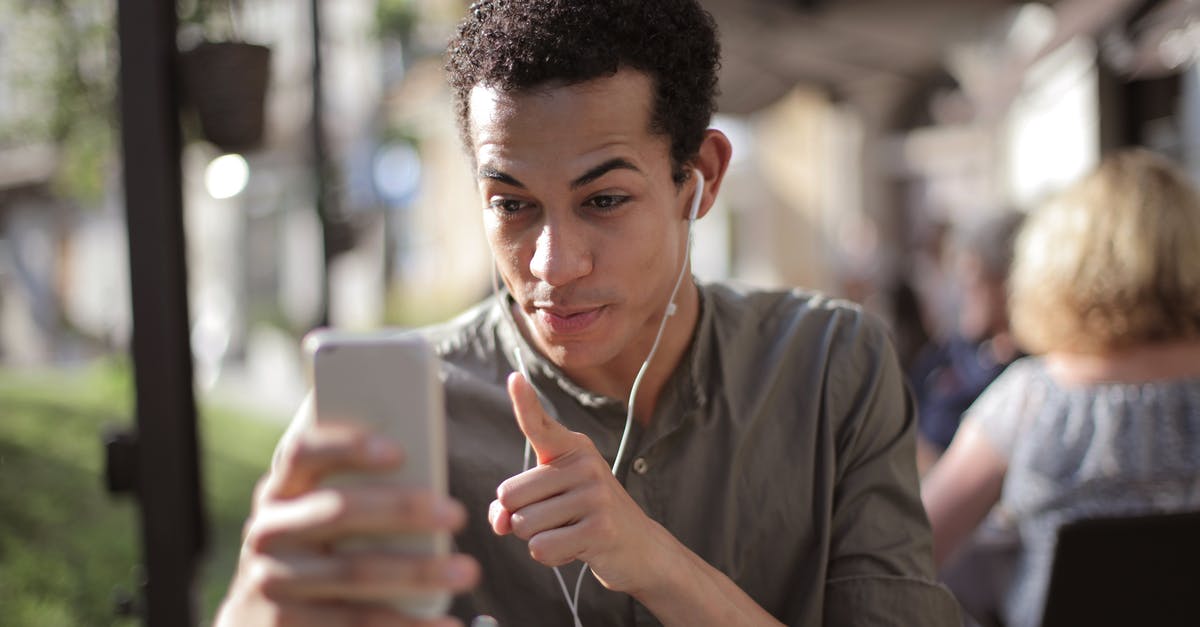 How to register with the ALDI talk mobile app? - Smiling African American male in casual clothing sitting in street cafe and talking via video chat while chilling in city and using mobile phone