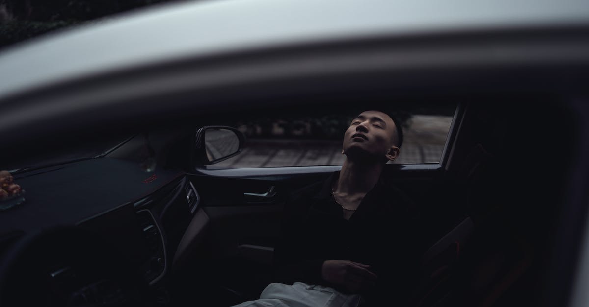 How to rent a car quiet on the inside - Netherlands - Through window of relaxed young Asian guy in casual clothes lying in modern car with closed eyes in evening