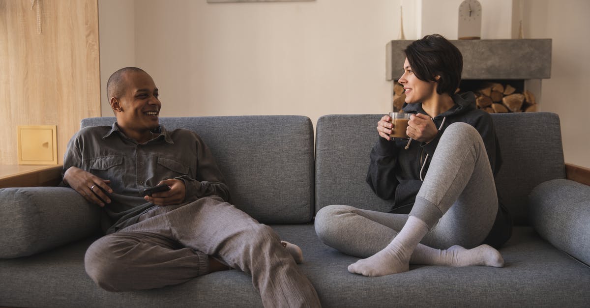 How to search for weekend flights? - Happy young multiracial couple taking on sofa at home