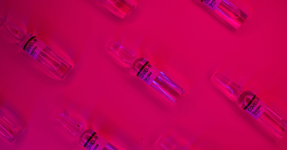 How to secure a roll-top closure bag? - Layout of doses of coronavirus vaccine in glass transparent vials placed on bright fuchsia background in studio