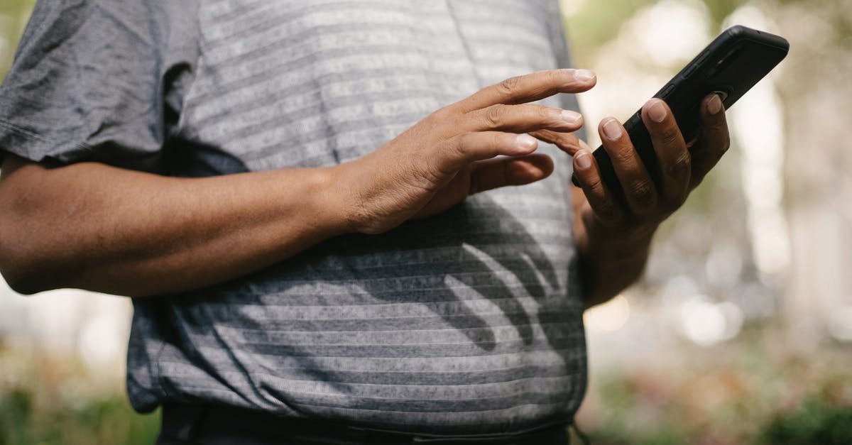 How to send the UK visa application in the USA? - Crop anonymous male in casual clothes using smartphone on blurred background of street