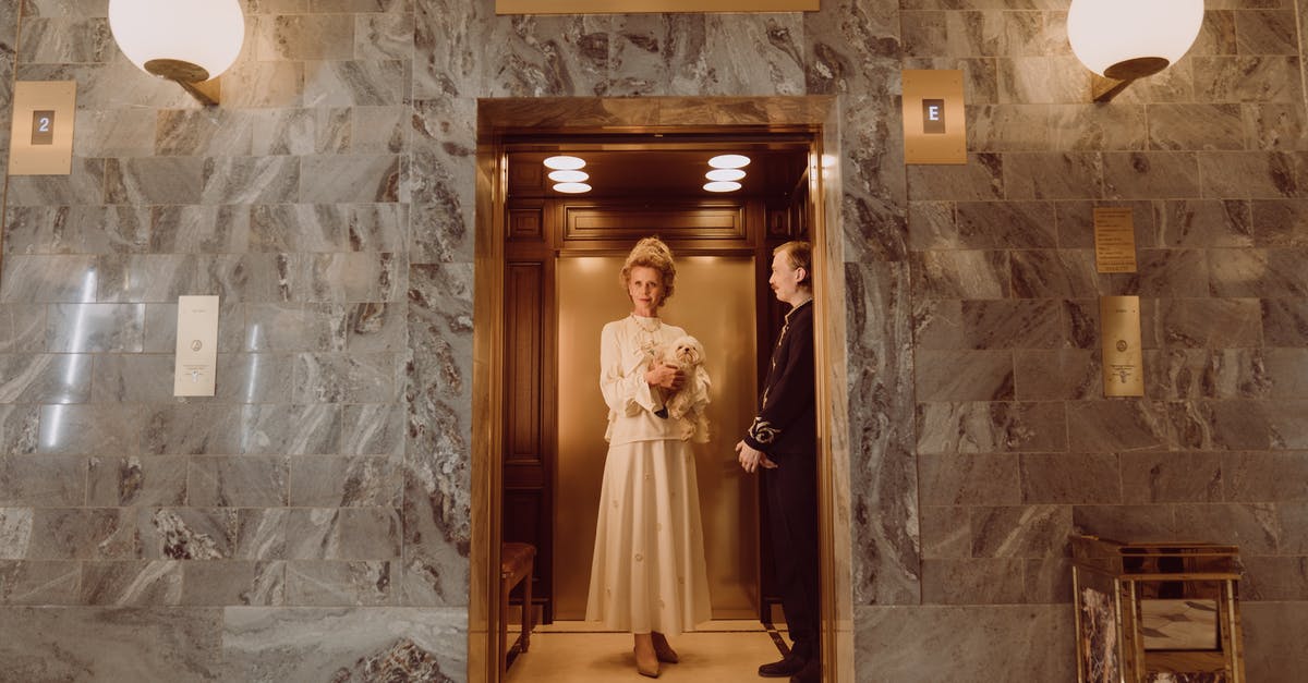 How to tip a concierge or a hotel porter? - Woman in White Dress Standing on Brown Wooden Door