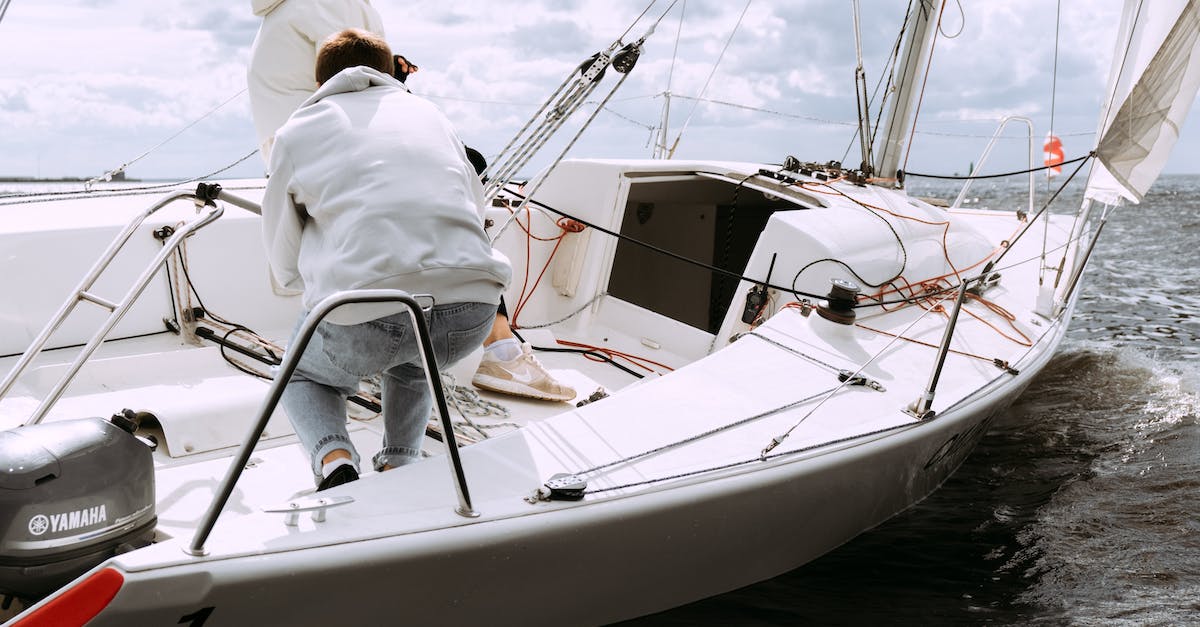 How to travel as a crew member on a ship? - Man in White Shirt Riding White and Blue Boat on Sea