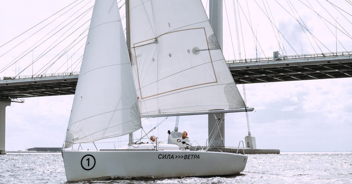 How to travel as a crew member on a ship? - Man in White Dress Shirt and Red Pants Sitting on White and Red Sail Boat during