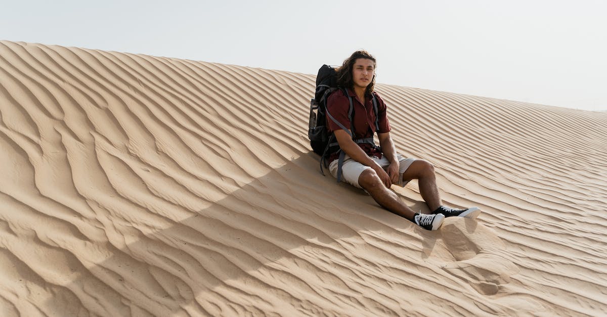 How to travel if you are stateless? - Woman in Black Shirt Sitting on Brown Sand