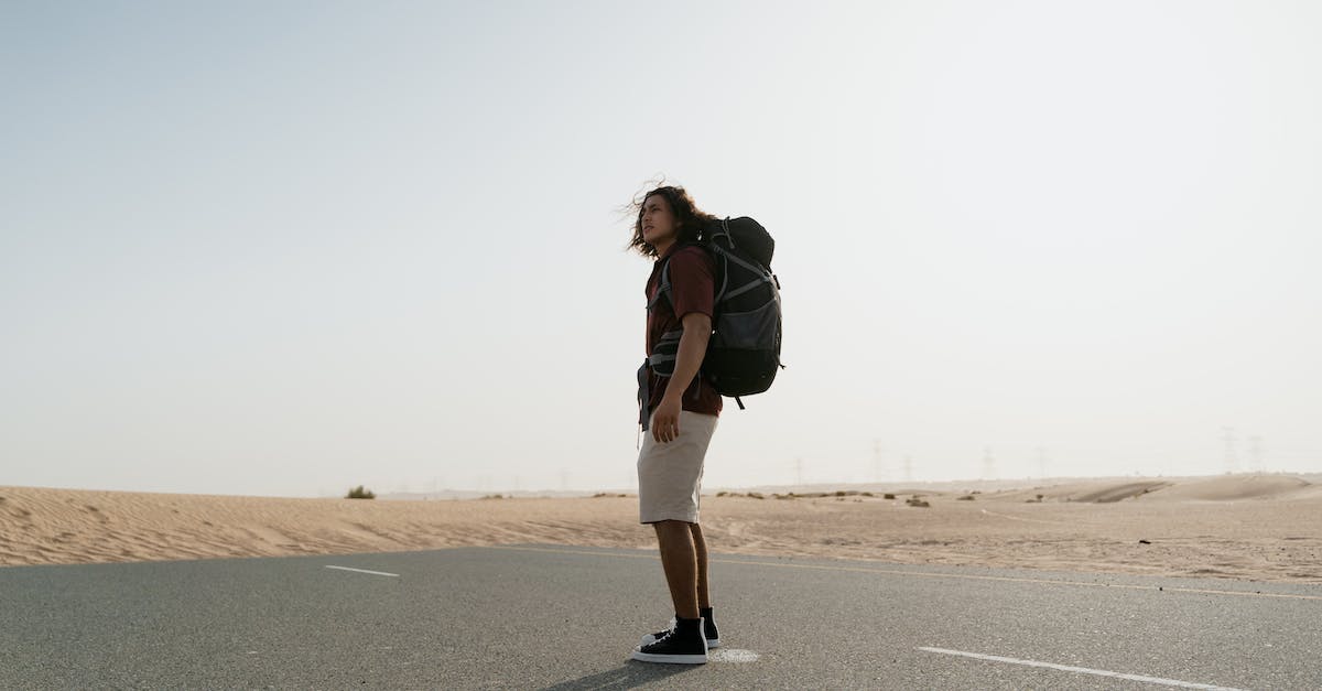 How to travel if you are stateless? - Woman in Black Jacket and White Pants Standing on Gray Asphalt Road