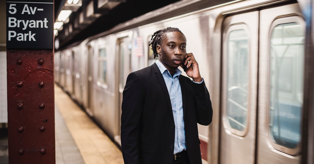 How to use a petrol/gas station in Greece? - Serious African American male in formal suit talking on smartphone while waiting for underground train to stop