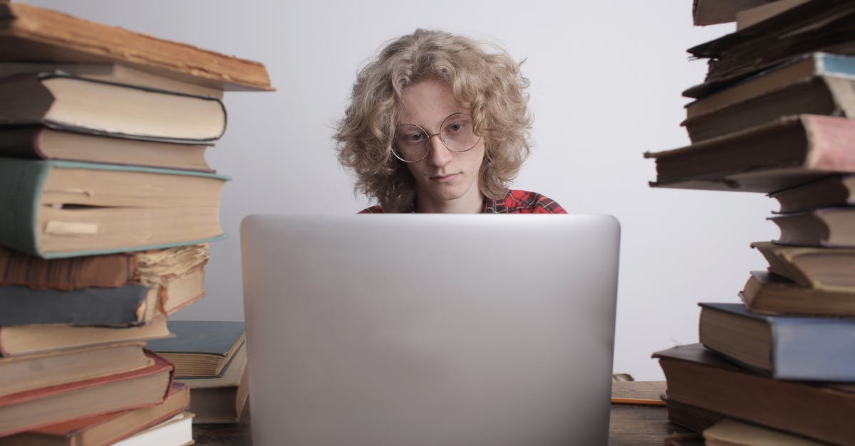 How to use cloud cover information to track auroras? - Concentrated male teenager in casual shirt and eyeglasses sitting at wooden table with books and using laptop while preparing for exams