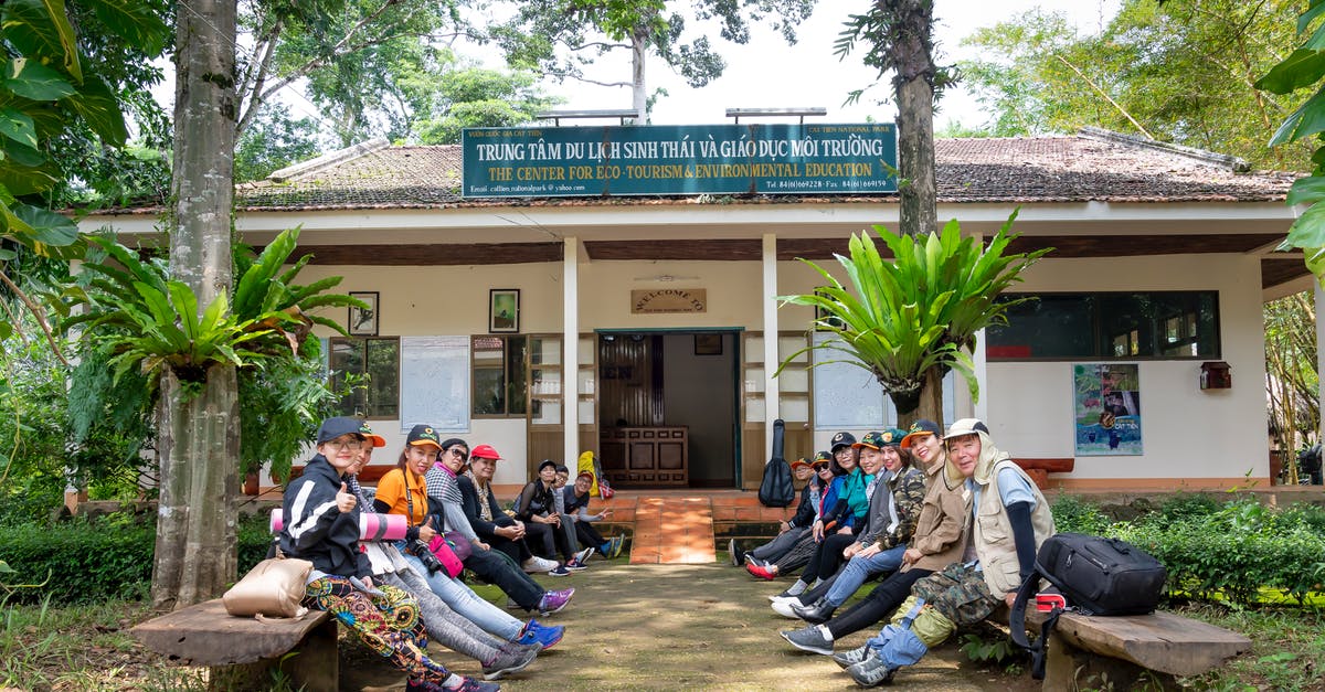 How to vet an overseas travel agency - Group of Asian tourists sitting on benches before hiking