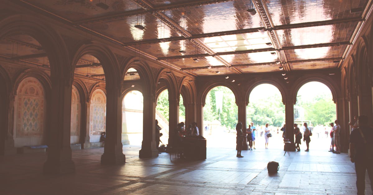 How to visit Malbork Castle from Gdansk? - Tourists standing near beautiful ornamental pavilion decorated with arches and mosaic during sunny summer day