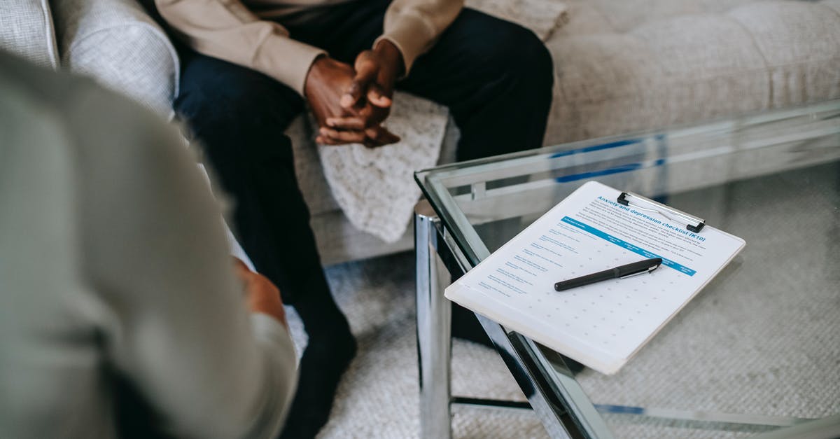 How to visit Stonehenge from Bristol or Bath? - From above of unrecognizable ethnic male patient with clasped hands sitting near anonymous psychologist in office with glass table and clipboard with notes