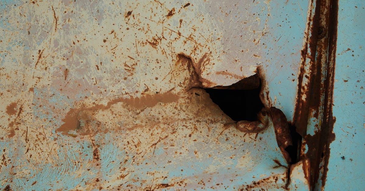 How to visit the Hindenburg Crash Site? - Old rusty metal surface of blue color with scratches and hole in abandoned building