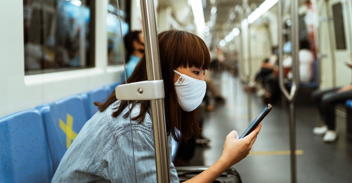 Hungarian train (MÁV) tickets online? - Woman Wearing a Face Mask and Holding a Smartphone