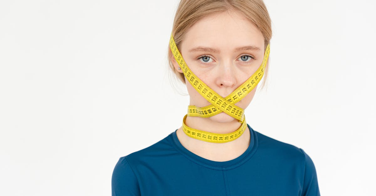 I'm worried about fitting into armrest [duplicate] - Unhappy young female with centimeter tape on face looking at camera while standing on white background in studio during weight loss