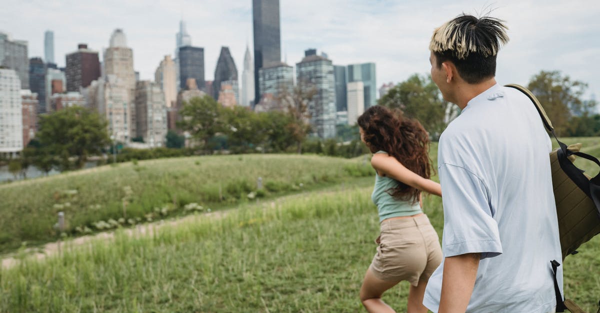 i94 when I have never been to the US - Side view of unrecognizable young female tourist holding hand of boyfriend and running in city park during romantic date in New York