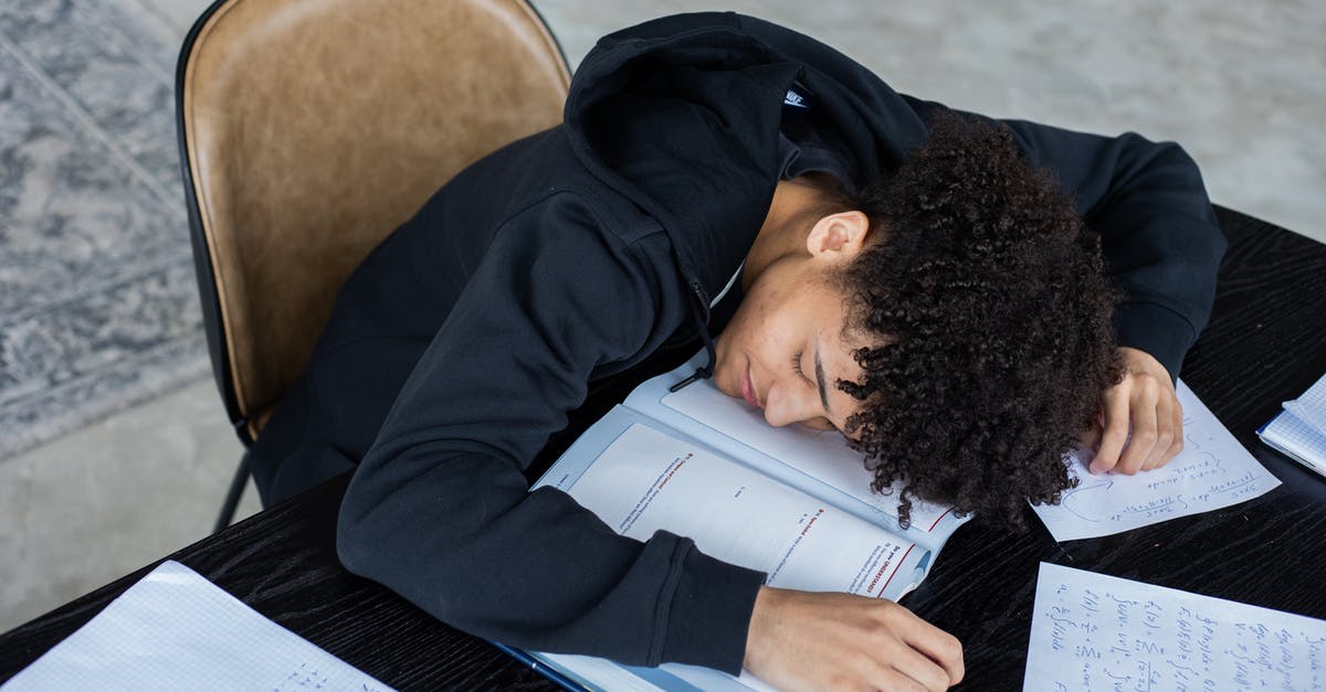 I am a graduate student traveling to France for a 5-day summer academic workshop at a university. Proof of accommodation? - High angle of exhausted African American student resting on opened textbook and papers while preparing for exam