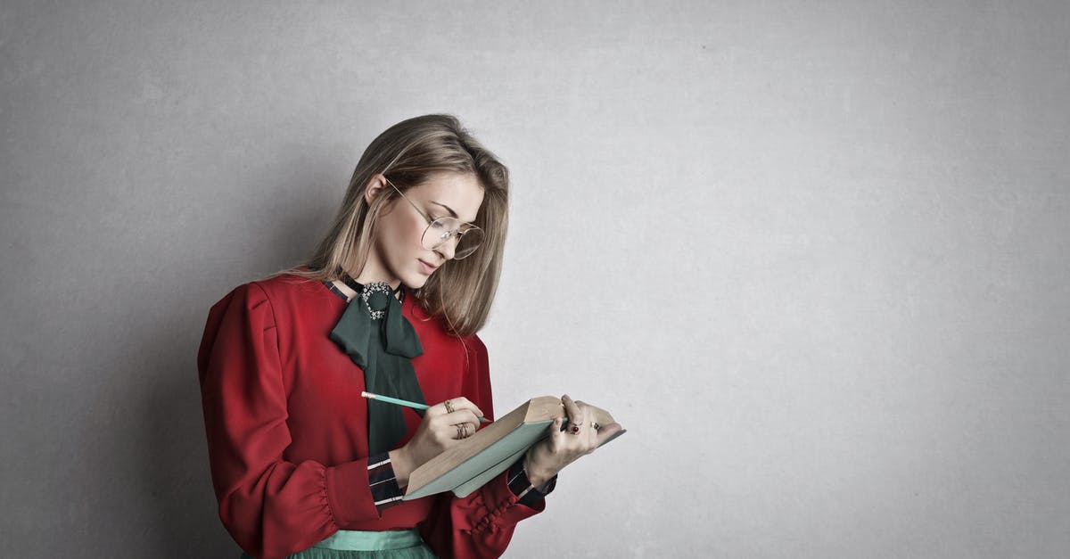 I am looking for a hotel search engine for rural areas - Pensive attentive woman in glasses and elegant vintage outfit focusing and taking notes with pencil in book while standing against gray wall