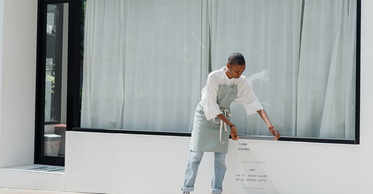 I am looking for a place in Scandinavia - Diligent black female worker setting signboard outside cafeteria at sunny day