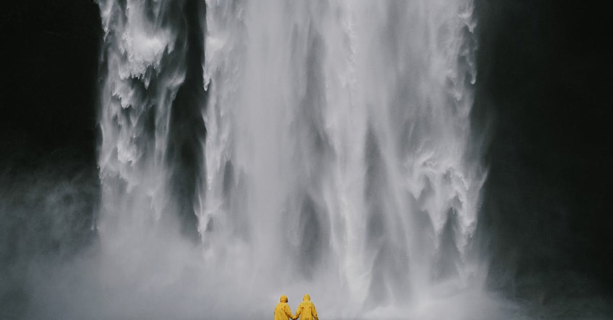 I have a stopover in Iceland with Iceland Air, do I have to collect and check back in my luggage? - Anonymous travelers holding hands against spectacular waterfall
