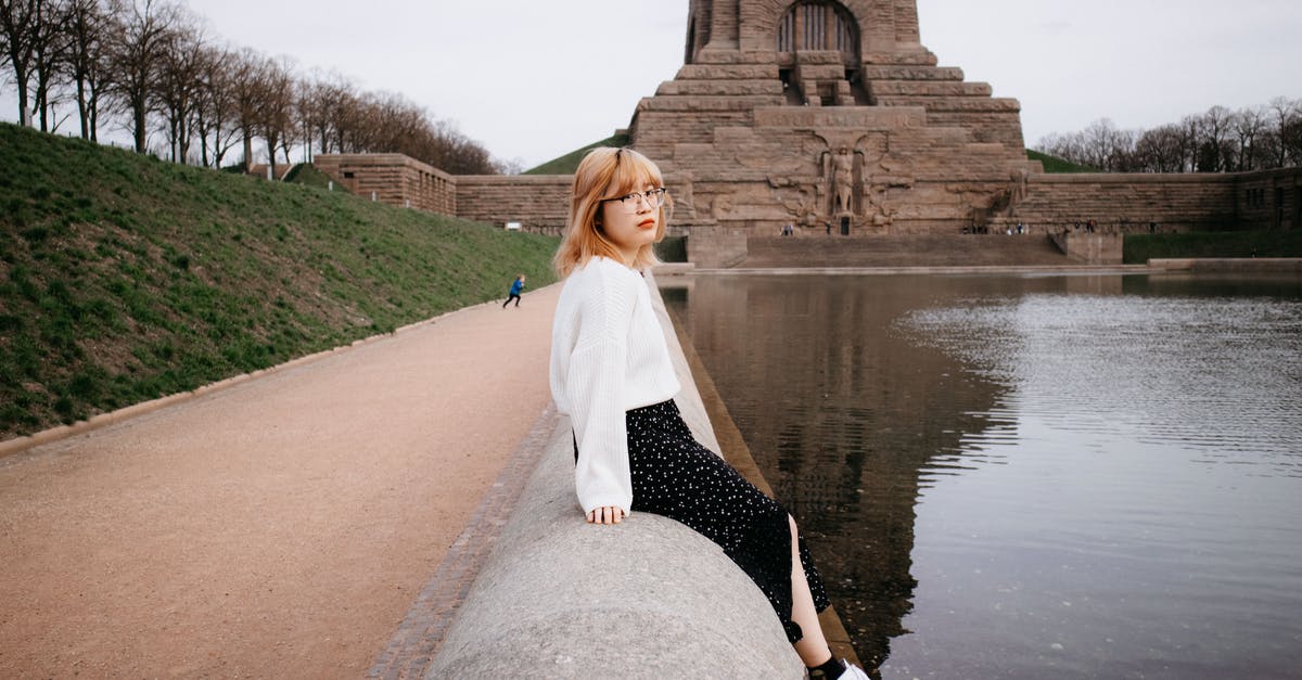 I want to visit my fiancee in Germany - A Woman in White Knitted Sweater Sitting Beside the Lake