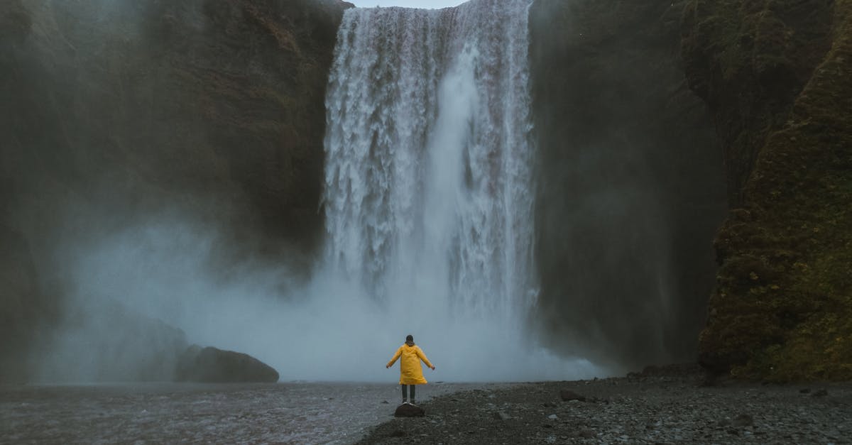 Iceland - Visiting fjords from Reykjavík in 1 day - Person in Yellow Clothes by the Waterfall