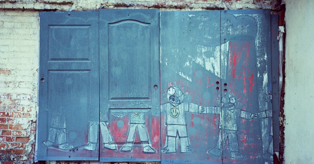 Identify location of old painting - Shabby wooden door with graffiti on weathered stone wall