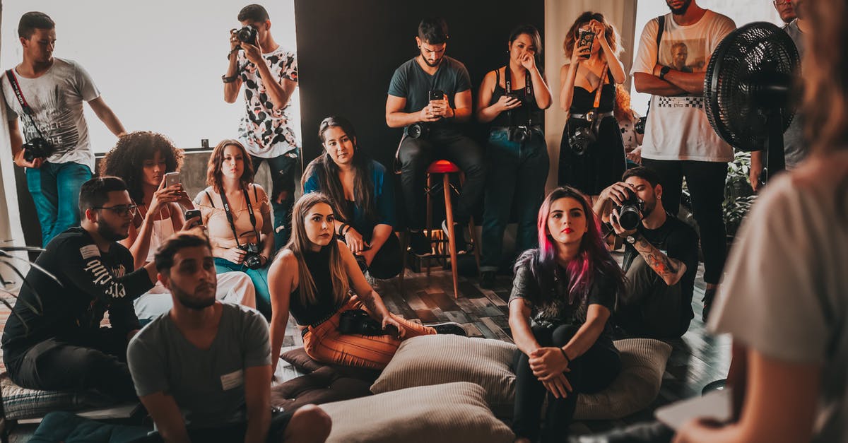 In Japan, is it considered rude to talk on the train? - Group of multiethnic young people wearing casual clothes gathering together in spacious studio and listening attentively to female speaker