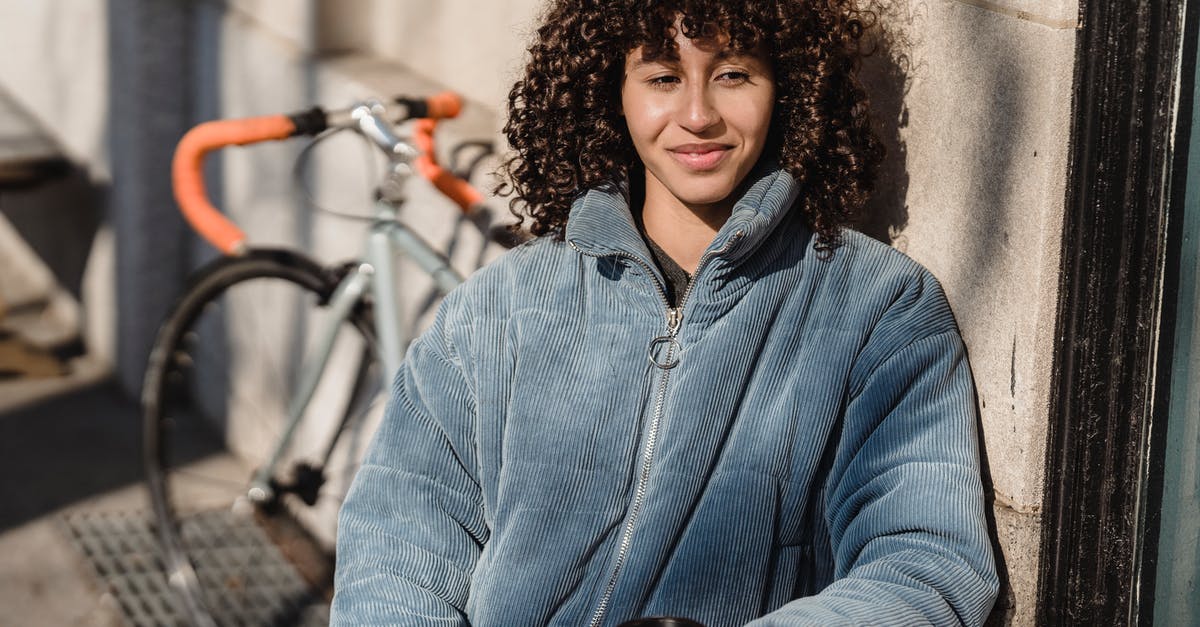 In Mongolia, what kind of vehicle is a jeep? - Contemplative ethnic female in jacket with hot drink to go looking away while sitting at urban cafe table in sunlight