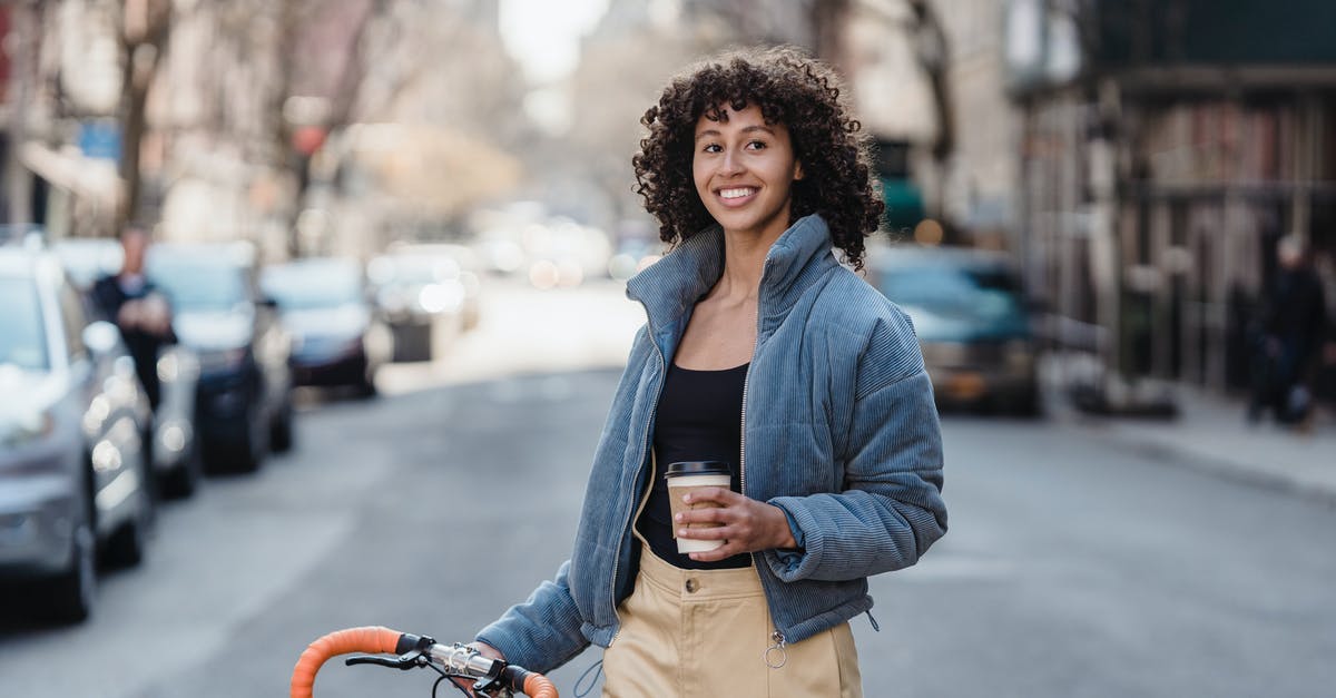 In Mongolia, what kind of vehicle is a jeep? - Smiling ethnic woman with coffee and bike on urban road